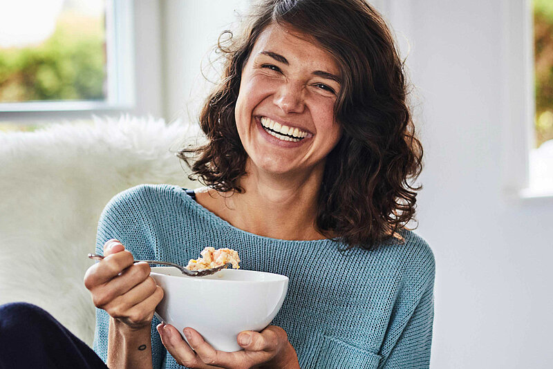 Abbildung einer ästhetisch lachenden Frau beim Frühstück